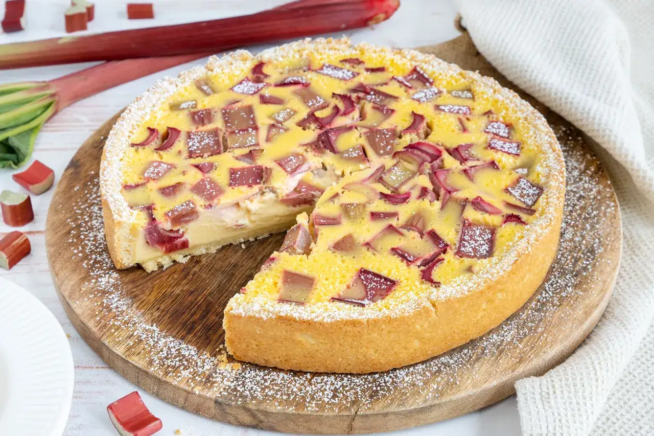 Ein k&ouml;stlicher Rhabarber Schmand Kuchen mit einem goldbraunen Boden, belegt mit saftigen Rhabarberst&uuml;cken und Puderzucker best&auml;ubt.