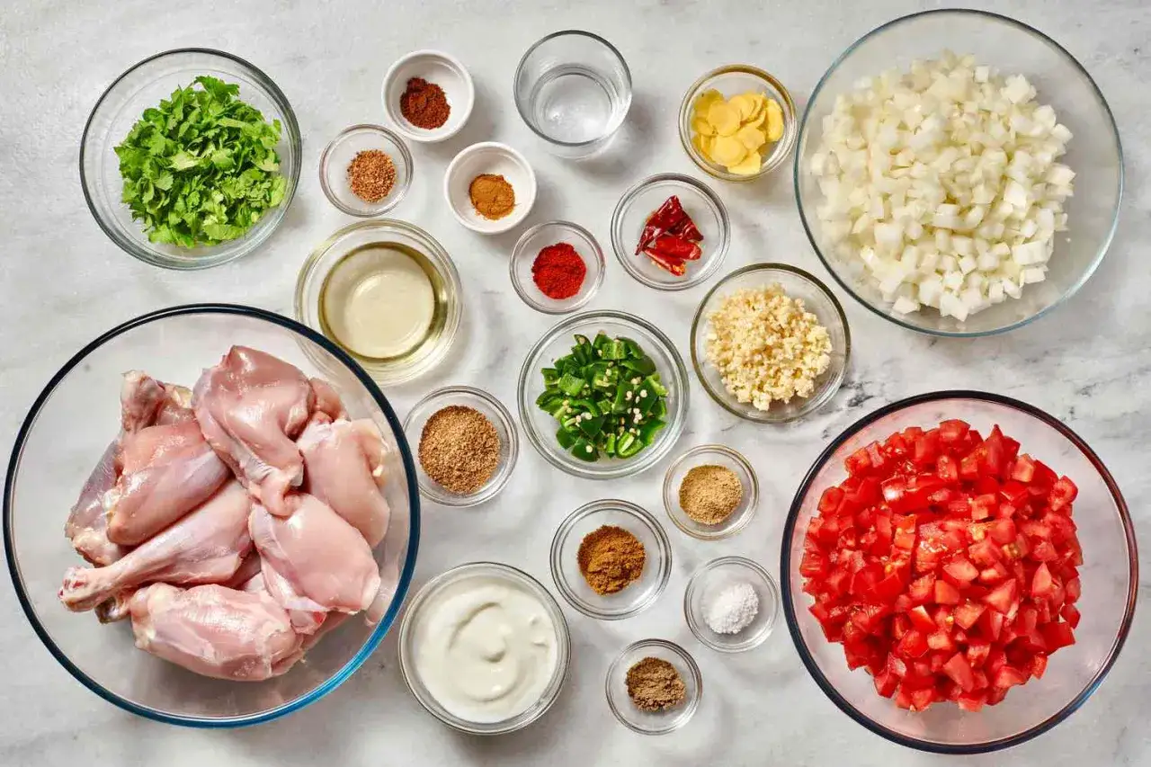Zutaten f&uuml;r ein indisches Curry Rezept: H&auml;hnchenteile, gew&uuml;rfelte Zwiebeln, Tomaten, Ingwer, Knoblauch, Chili, Joghurt und Gew&uuml;rze.