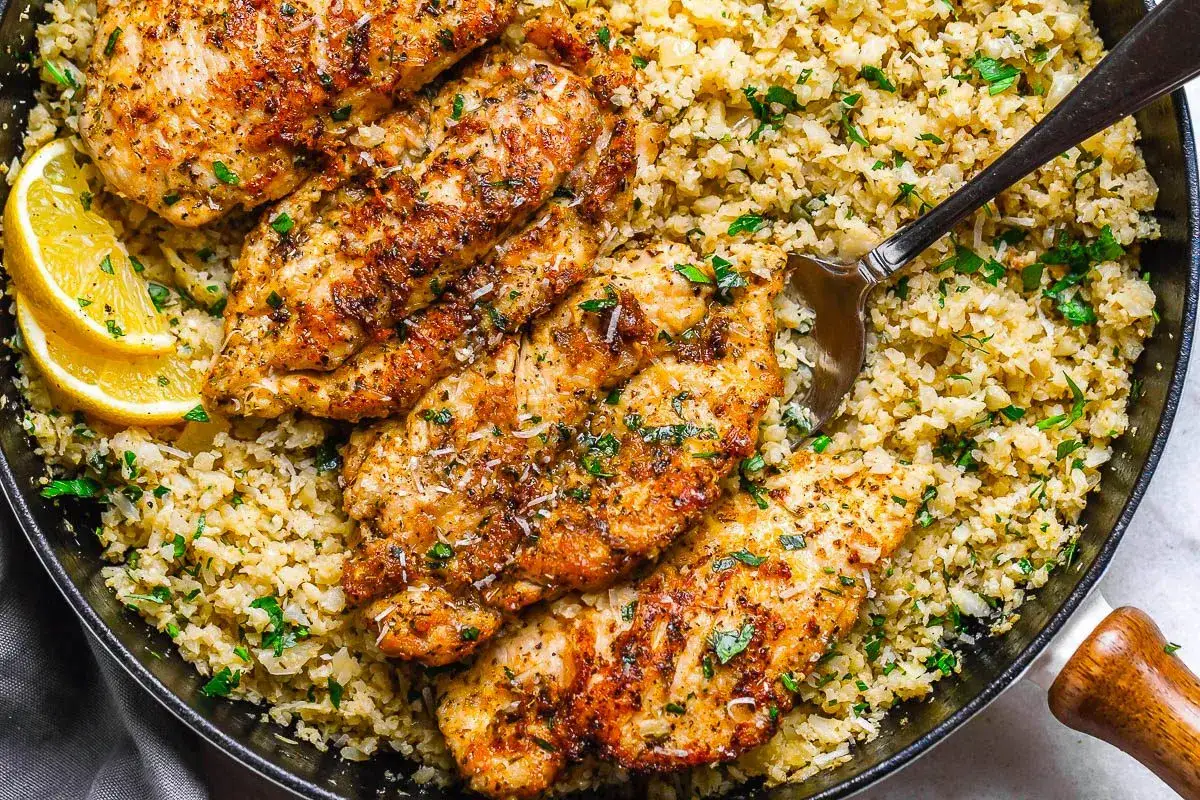 Gebratene H&auml;hnchenbrust auf Blumenkohlreis, ein schnelles und warmes low carb rezept f&uuml;r das Abendessen. Mit Zitrone und Petersilie garniert.