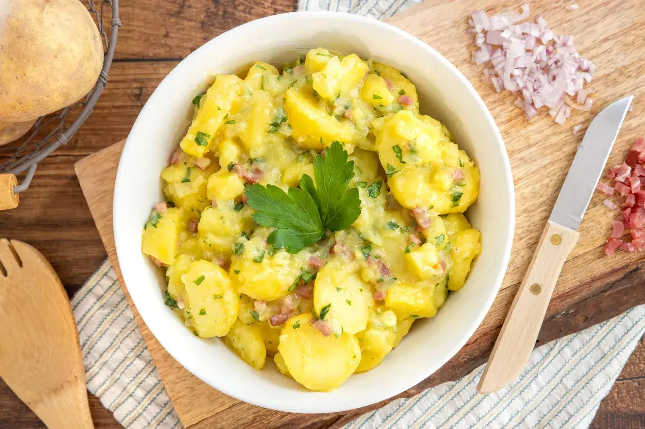 Ein Sch&uuml;ssel voller Kartoffelsalat, bereit f&uuml;r ein leckeres Kartoffelsalat Rezept. Mit Speck und Petersilie garniert.