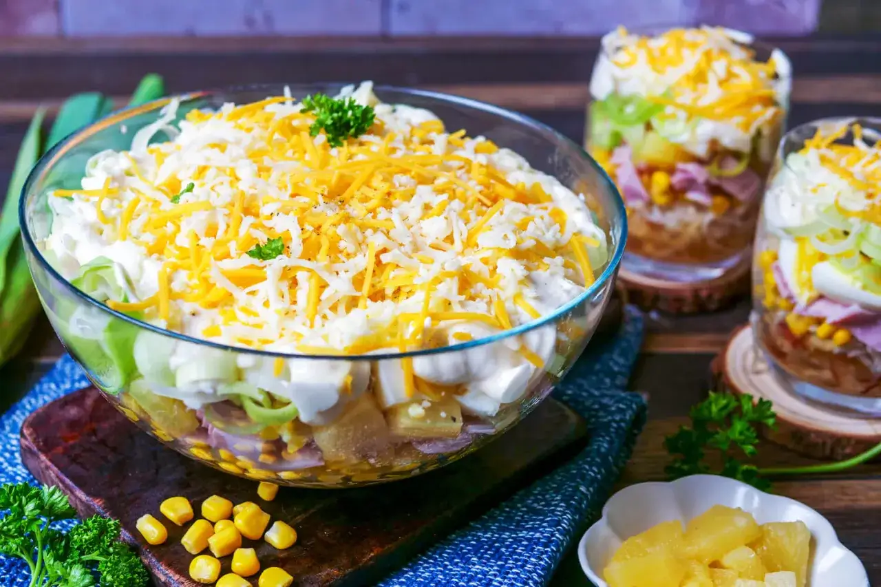 Schichtsalat-Rezept mit Miracel Whip: Schichten aus Ei, Schinken, Mais und Lauch, gekr&ouml;nt mit K&auml;se.