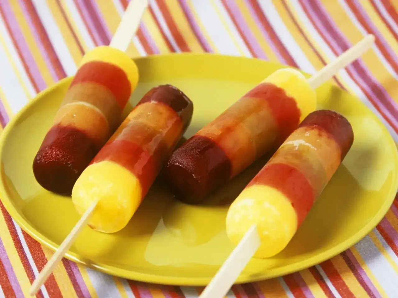 Bunte Fruchteis-Schichten zum Selbermachen auf gelber Platte.