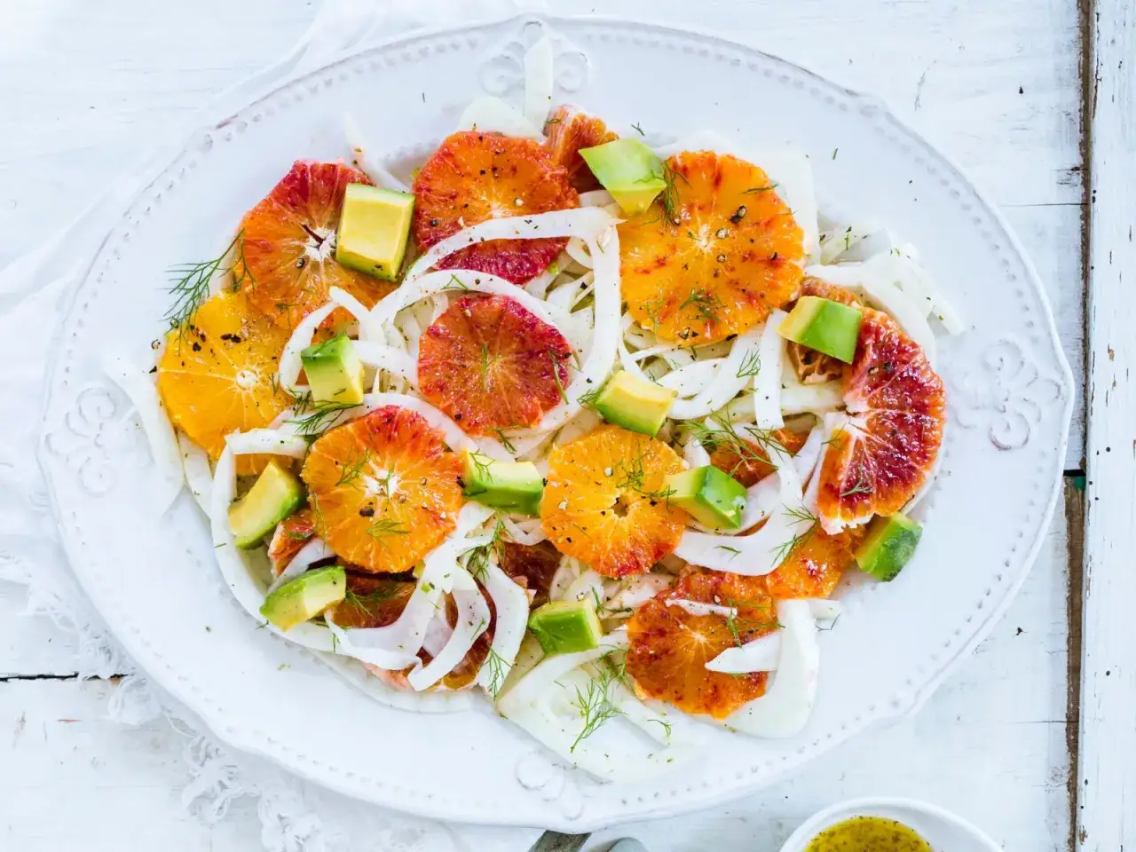 Erfrischender Fenchel-Orangen-Salat mit Avocado und Dill. Bunte Scheiben von Blutorangen und Orangen liegen auf hauchd&uuml;nnem Fenchel.