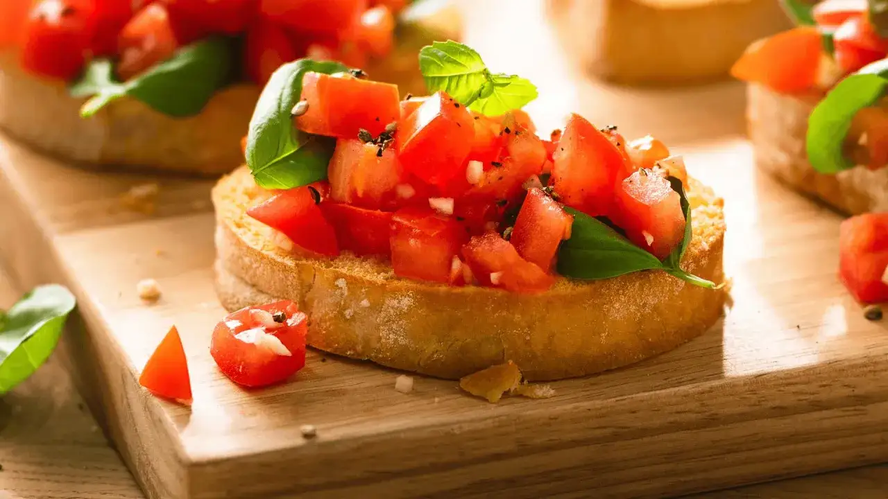 Frisches Bruschetta Rezept: geröstetes Brot mit Tomatenwürfeln, Basilikum und Knoblauch, auf einem Holzbrett serviert.