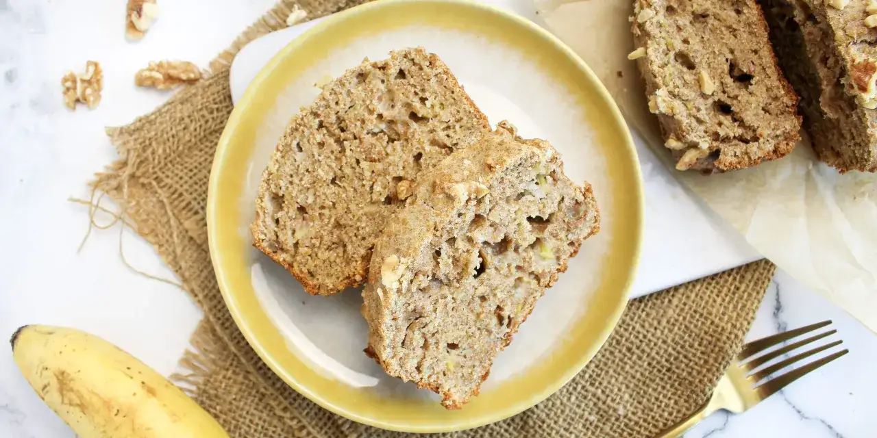 Zwei Scheiben Bananenbrot mit N&uuml;ssen auf einem gelben Teller, ein Beweis f&uuml;r ein k&ouml;stliches Bananenbrot Rezept ohne Zucker.