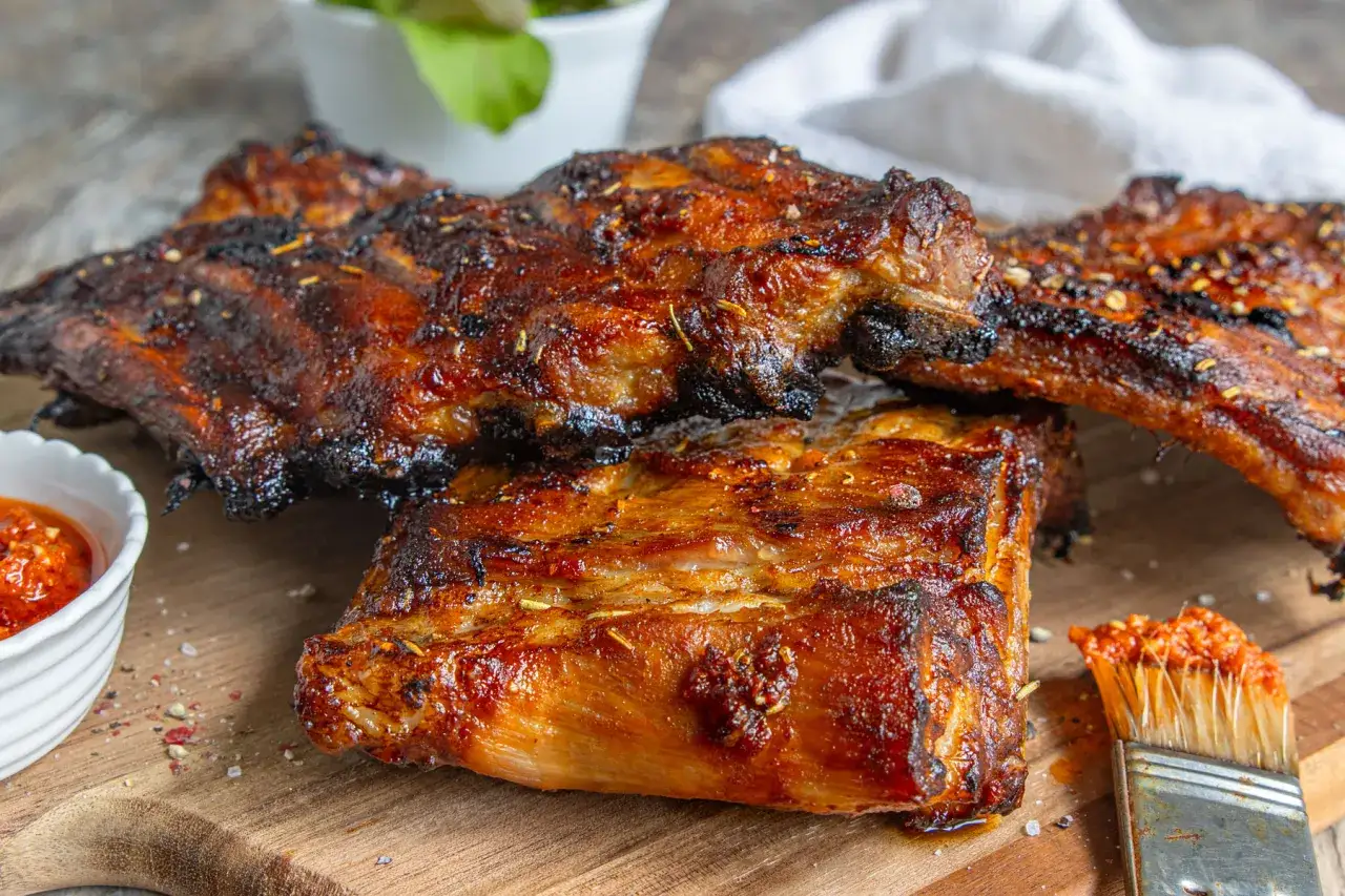 Saftige spareribs im backofen, goldbraun und knusprig, mit einer würzigen Marinade und einem Pinsel zum Nachwürzen.