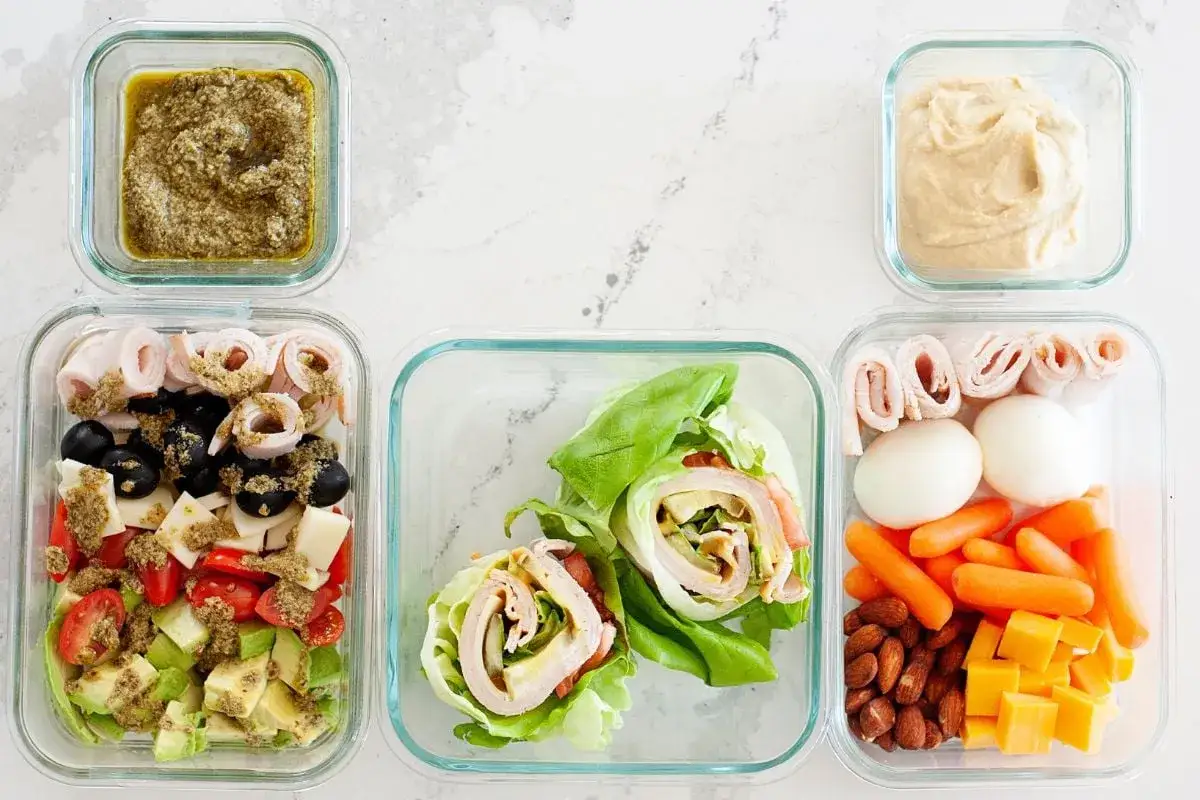 Vorbereitetes low carb mittagessen: Salat mit Pesto, Wraps, Eier, Gemüse und Nüsse.