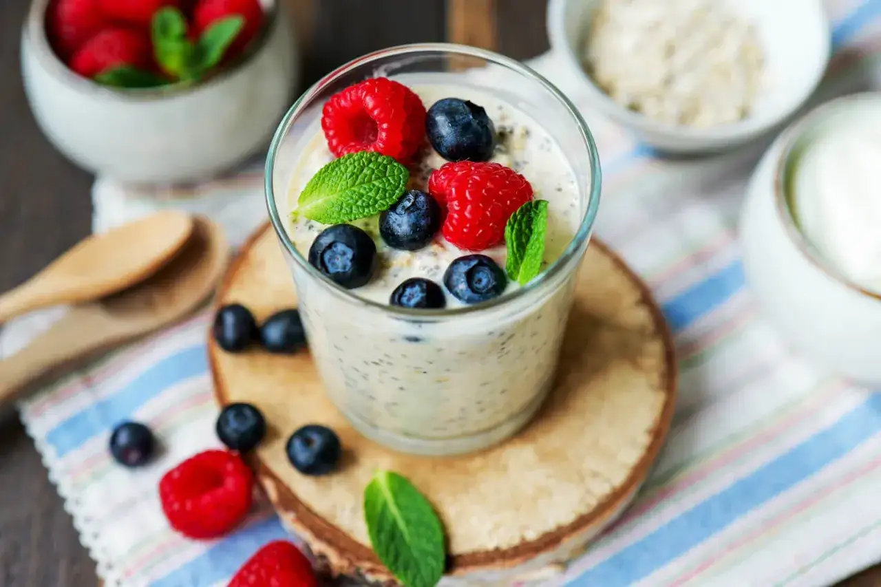Ein Glas Overnight Oats mit Joghurt, garniert mit frischen Beeren und Minze. Perfekt für ein schnelles Frühstück.