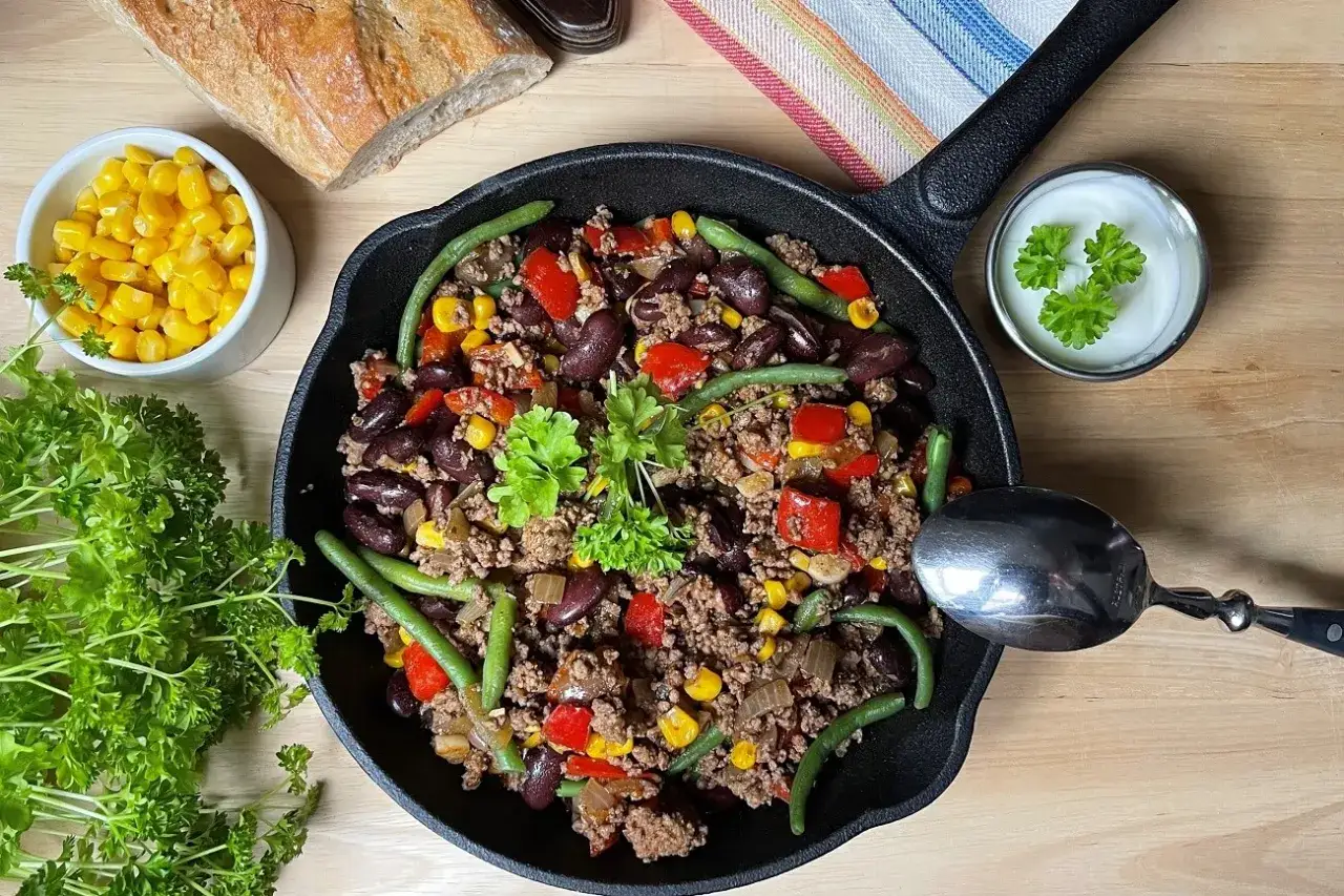 Herzhafte Hackfleischpfanne mit Bohnen, Mais und Paprika – ein Beweis für schnelle Hackfleisch Rezepte. Dazu frische Petersilie und ein Klecks Sour Cream.