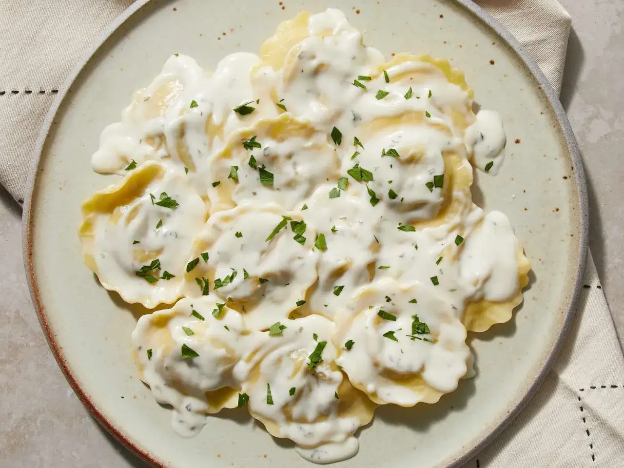 Ravioli in cremiger Sahnesauce, garniert mit Petersilie. Ein k&ouml;stliches Gericht mit Sahne, das zum Genie&szlig;en einl&auml;dt.