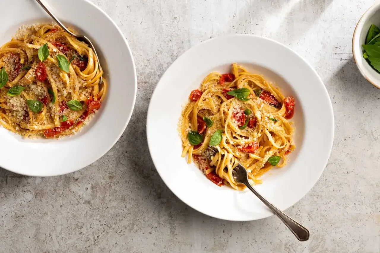 Zwei Teller Pasta mit Tomaten und Basilikum, bestreut mit Parmesan. Perfekt f&uuml;r schnelle einfache gerichte.