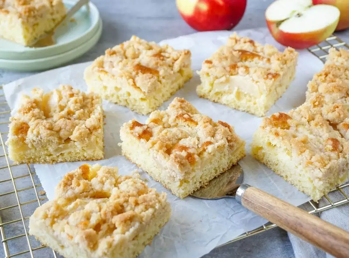Saftiger apfelkuchen vom blech mit Streuseln, frisch gebacken und auf einem Gitterrost angerichtet.