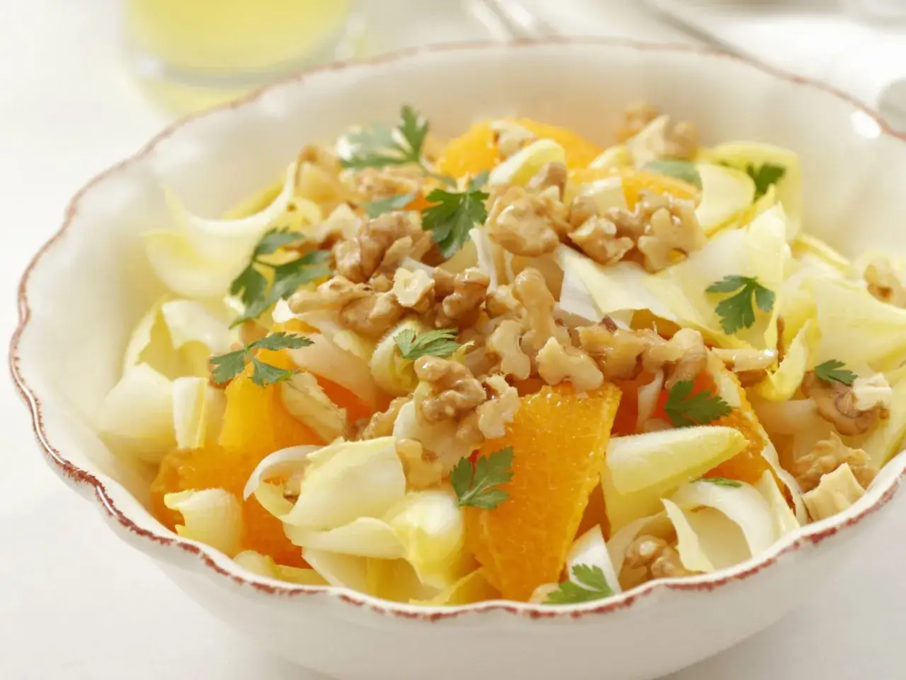Ein erfrischender chicoree salat mit saftigen Orangenspalten und knackigen Waln&uuml;ssen, garniert mit Petersilie.