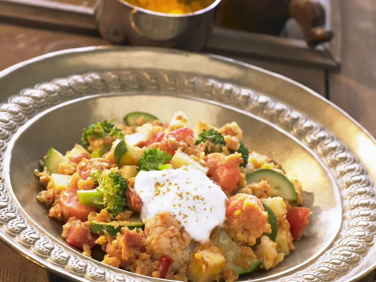 Herzhaftes Gericht ohne Fleisch mit Linsen, Brokkoli, Zucchini und Tomaten, garniert mit Joghurt.