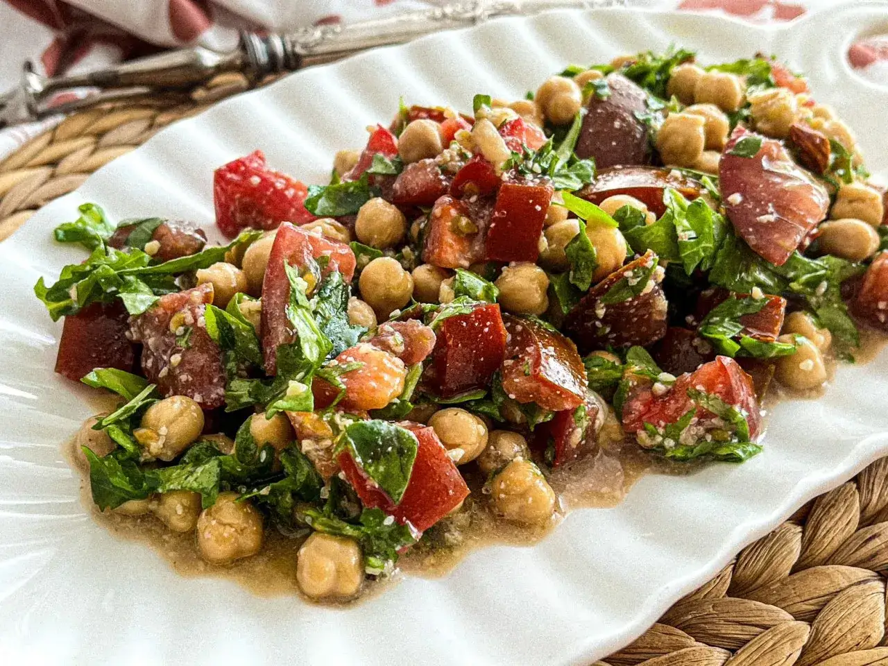 Mediterraner Salat mit Kichererbsen, getrockneten Tomaten und Rucola, appetitlich auf einem weißen Teller angerichtet.