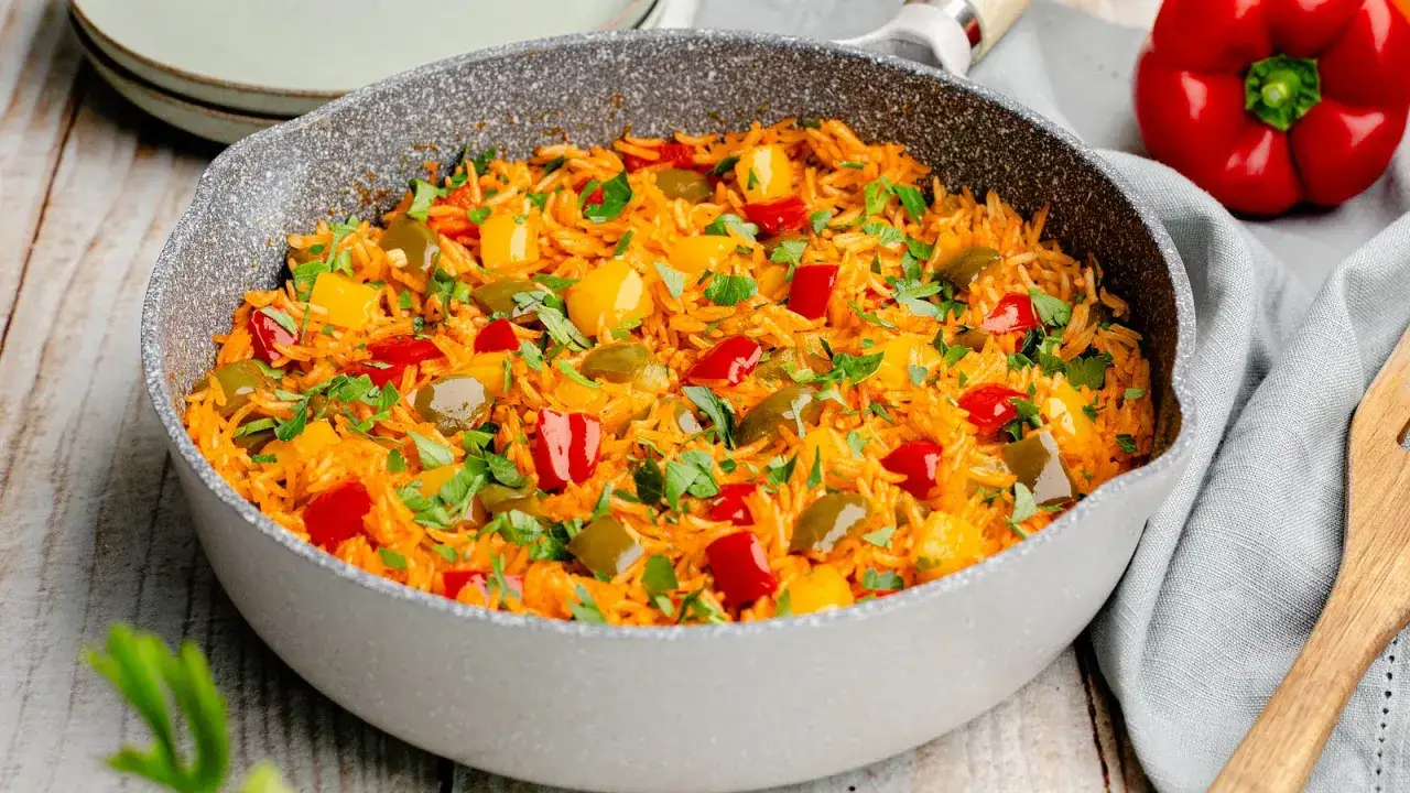 Bunte Paprika Reis Pfanne, garniert mit frischer Petersilie. Ein köstliches Gericht, das Farbe auf den Tisch bringt.
