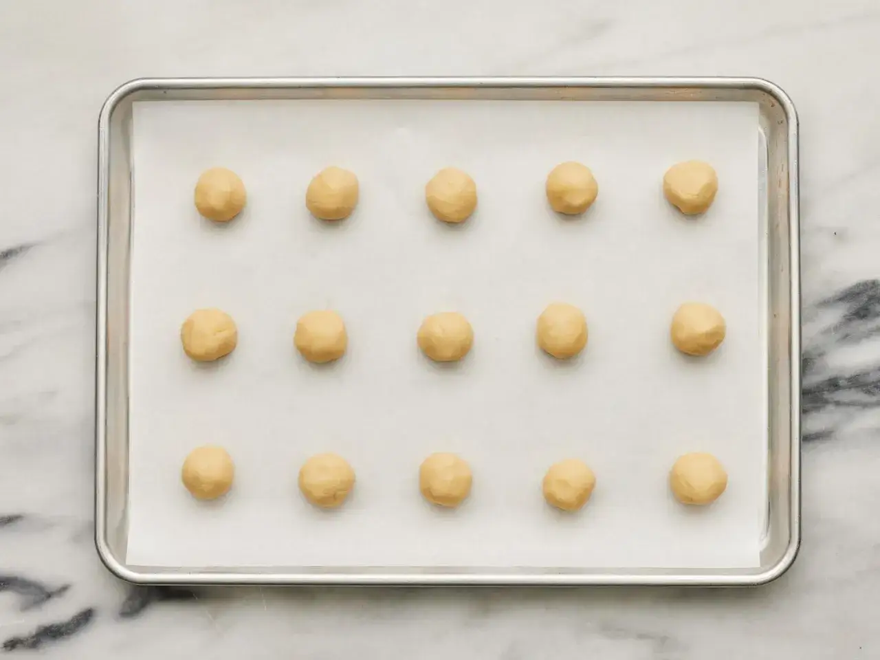 Vorbereitung f&uuml;r ein einfaches Cookies Rezept: Teigkugeln liegen auf einem Backblech, bereit zum Backen.