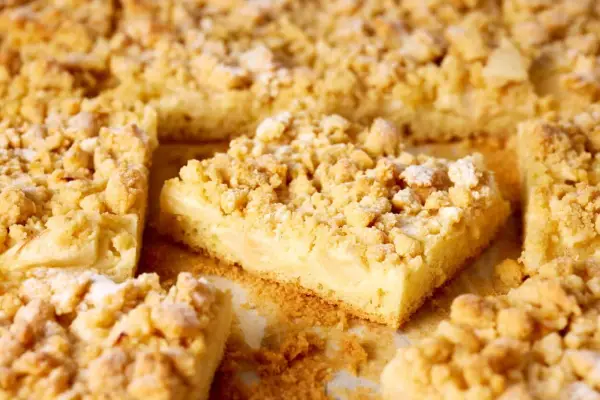 Saftiger Apfelkuchen mit Vanillepudding und knusprigen Streuseln, bestäubt mit Puderzucker. Ein Genuss für jeden Kaffeetisch.