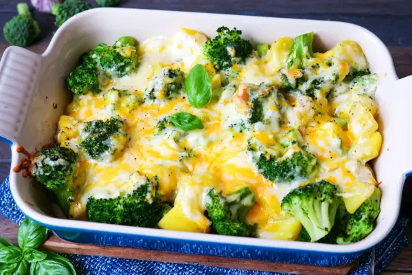 Herzhaftes Kartoffel Brokkoli Gratin, überbacken mit geschmolzenem Käse und garniert mit frischem Basilikum.